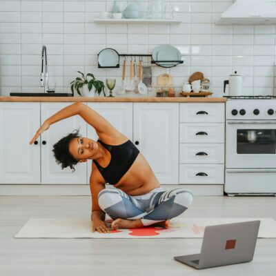 A woman exercises with online yoga videos in her stylish kitchen.